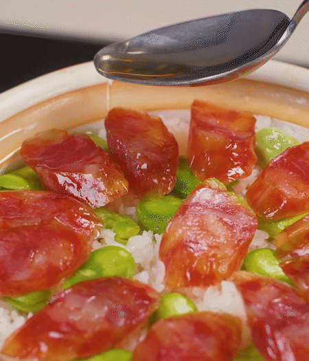 大米出現(xiàn)小孔時(shí)開蓋放香腸，往鍋邊淋入少許油，再燜煮8~10分鐘左右。