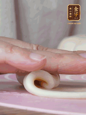 做面劑 油皮按扁，中間包入一個(gè)油酥，邊緣收緊捏死。包好的面劑按扁，用搟面杖搟壓成橢圓形。從底部向上卷成筒狀，用保鮮膜蓋好松弛15分鐘，再把筒狀縱向搟壓成長(zhǎng)條狀。再卷一次，松弛20分鐘