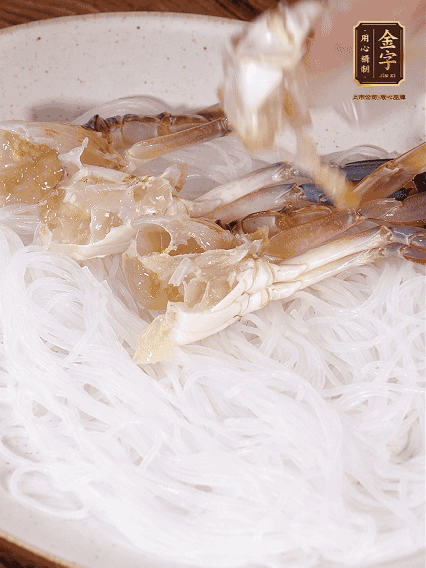 盤(pán)底墊上粉絲，擺上梭子蟹、火腿片，撒姜粒，淋上蒸魚(yú)豉油、花雕酒調(diào)味腌制15分鐘