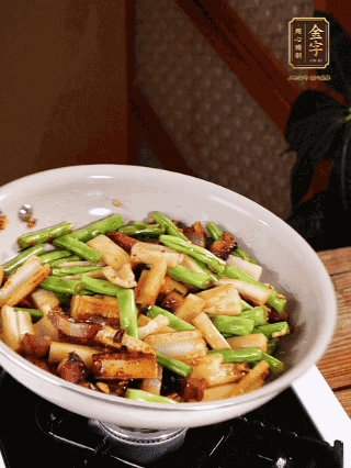 油熱下蒜末、干辣椒、醬肉煸炒出香味，依次下藕條、豆角翻炒均勻